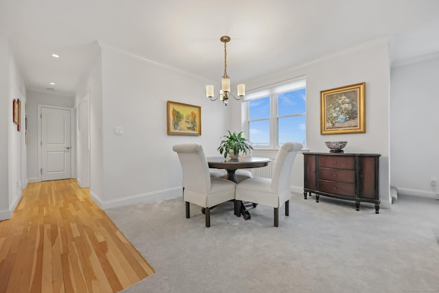 carpeted dining room with a notable chandelier, crown molding, and baseboards