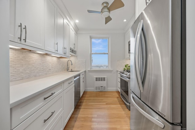 kitchen with a sink, white cabinetry, stainless steel appliances, and light countertops