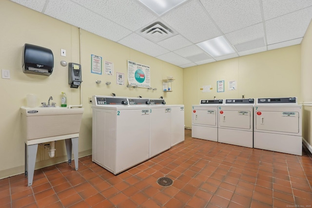 shared laundry area featuring dark tile patterned flooring, washing machine and dryer, and visible vents