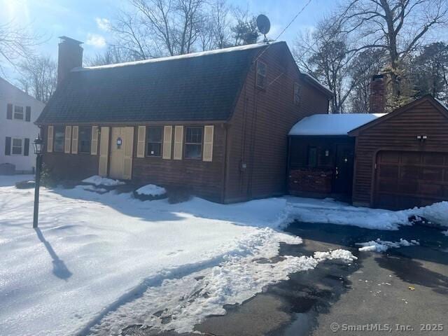 view of front of property featuring a garage, a chimney, and a gambrel roof