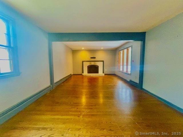 unfurnished living room with a fireplace, baseboards, and wood finished floors