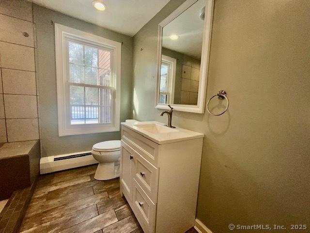 bathroom with toilet, wood finished floors, vanity, baseboards, and baseboard heating