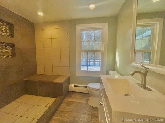 bathroom with recessed lighting, toilet, vanity, and baseboard heating