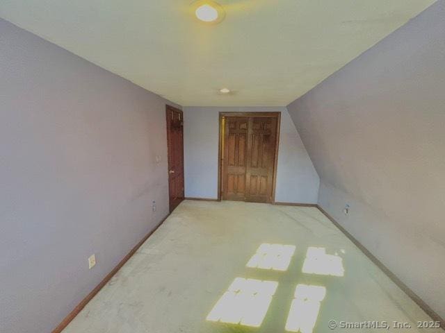 bonus room featuring vaulted ceiling, light colored carpet, and baseboards