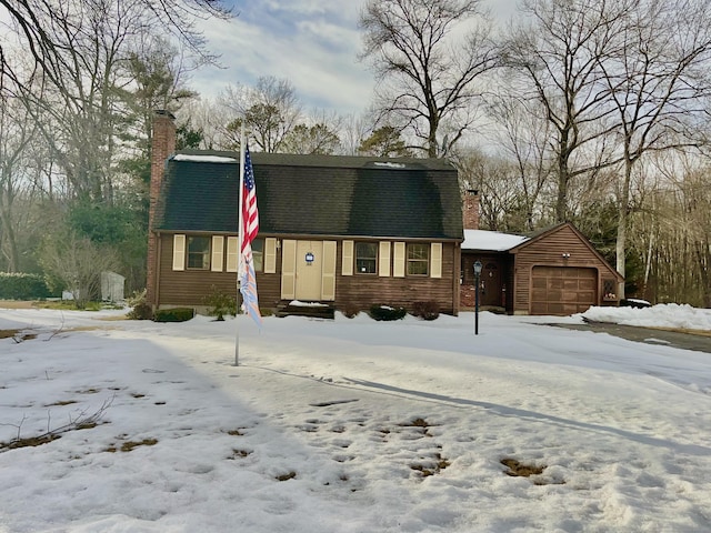 colonial inspired home with an attached garage, a chimney, and roof with shingles