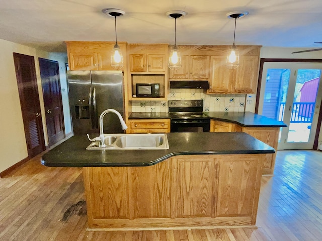 kitchen with range with electric cooktop, under cabinet range hood, black microwave, stainless steel refrigerator with ice dispenser, and a sink