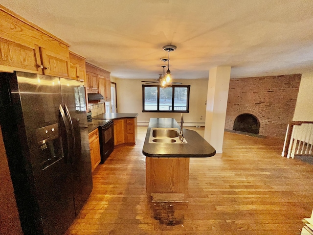 kitchen featuring a brick fireplace, a sink, stainless steel fridge, black range with electric cooktop, and under cabinet range hood