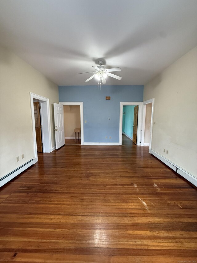 empty room with wood finished floors, a baseboard heating unit, baseboards, and a ceiling fan