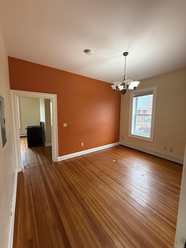 unfurnished room featuring baseboards, hardwood / wood-style floors, a chandelier, and a baseboard heating unit