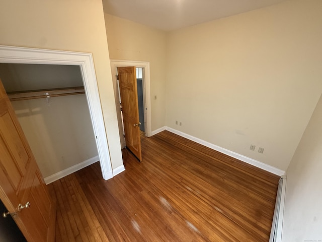 unfurnished bedroom with a closet, baseboards, and wood finished floors