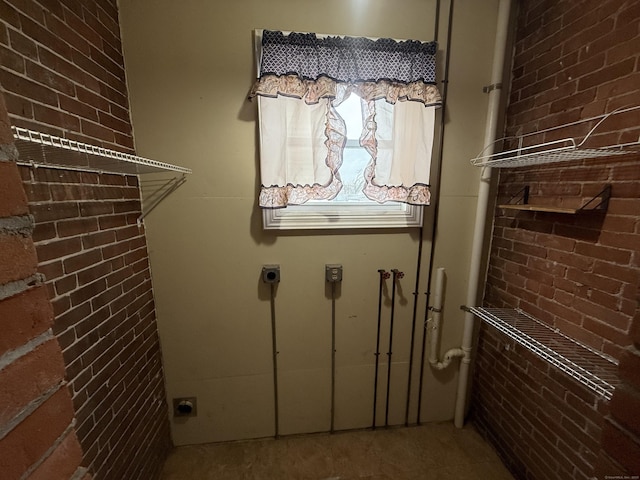 washroom featuring laundry area, brick wall, and hookup for an electric dryer