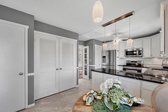 kitchen featuring decorative backsplash, decorative light fixtures, a peninsula, stainless steel appliances, and white cabinetry