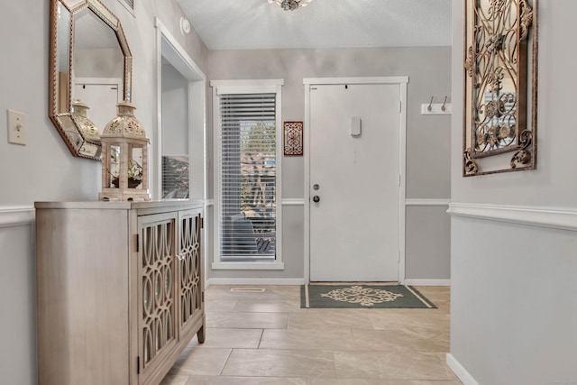 foyer entrance featuring a textured ceiling and baseboards