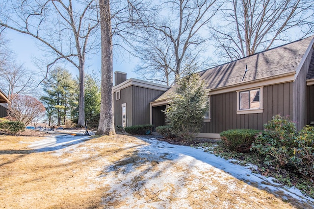 view of side of home featuring a shingled roof and a chimney