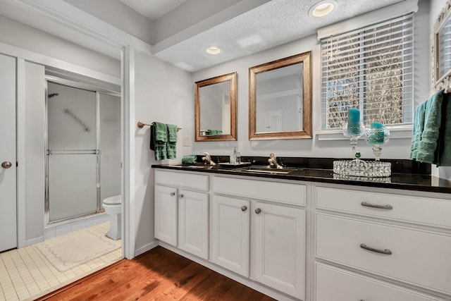 full bath featuring recessed lighting, toilet, vanity, a shower stall, and wood finished floors