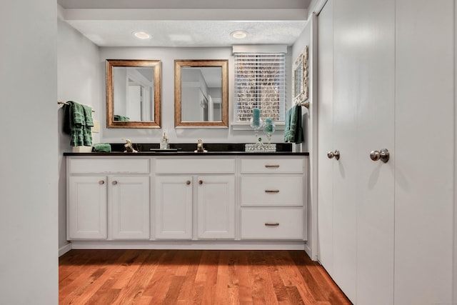 bathroom featuring a sink, double vanity, a textured ceiling, and wood finished floors