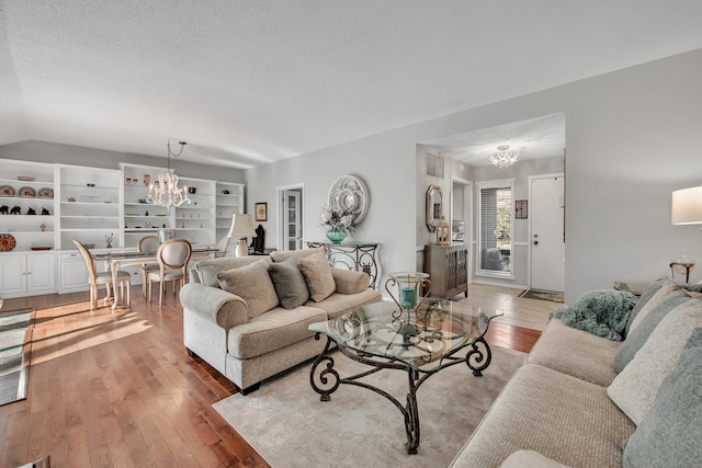 living area featuring wood-type flooring, visible vents, a notable chandelier, and a textured ceiling