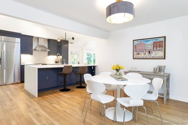 dining space featuring light wood-style floors, lofted ceiling with beams, and baseboards