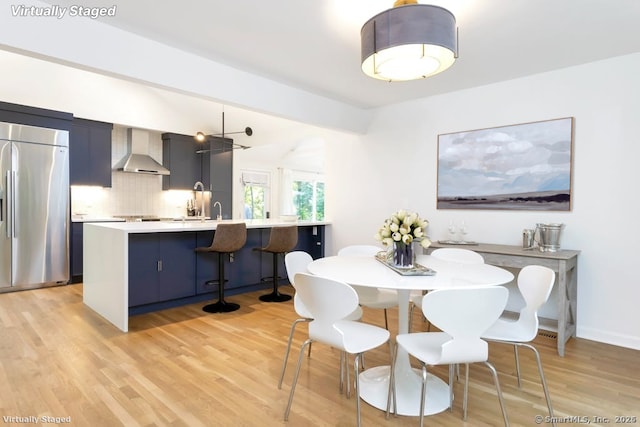 dining room featuring light wood finished floors, baseboards, and vaulted ceiling