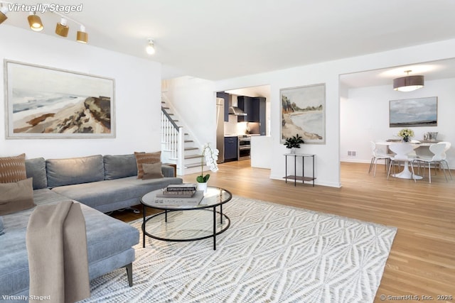 living room featuring visible vents, stairway, baseboards, and wood finished floors