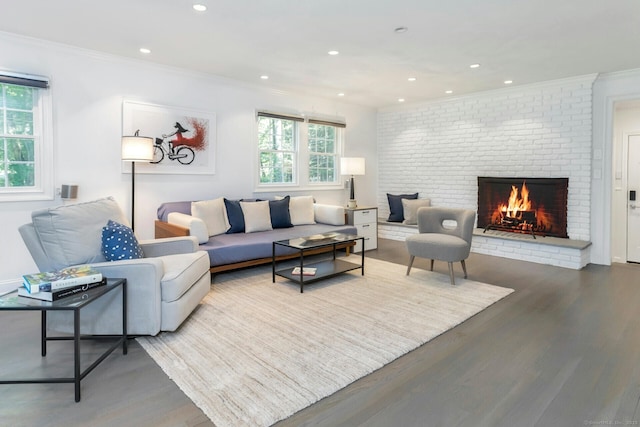 living area featuring ornamental molding, recessed lighting, a brick fireplace, and wood finished floors