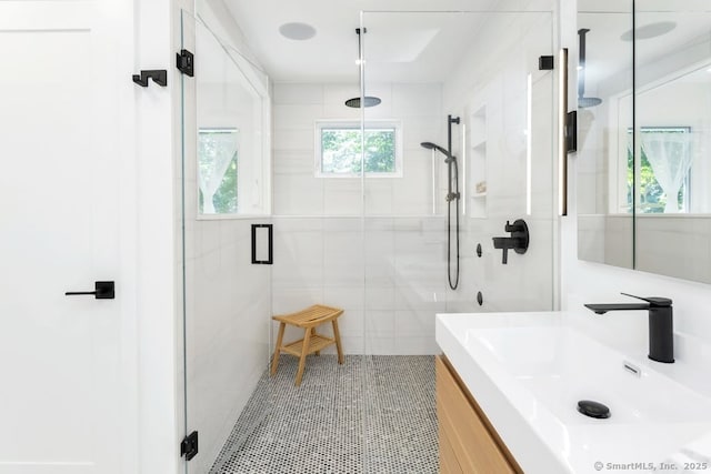 bathroom featuring a stall shower, tile patterned flooring, vanity, and tile walls