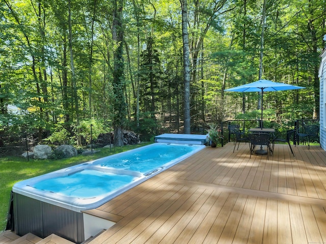 view of pool with a hot tub, a wooden deck, and outdoor dining space