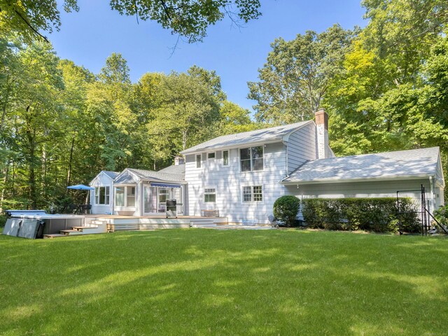 rear view of property with a lawn, a chimney, and a wooden deck