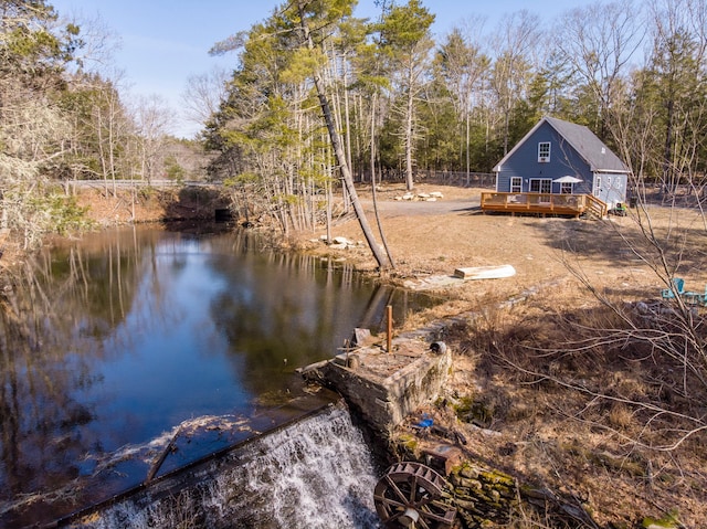 view of dock featuring a wooded view and a deck with water view