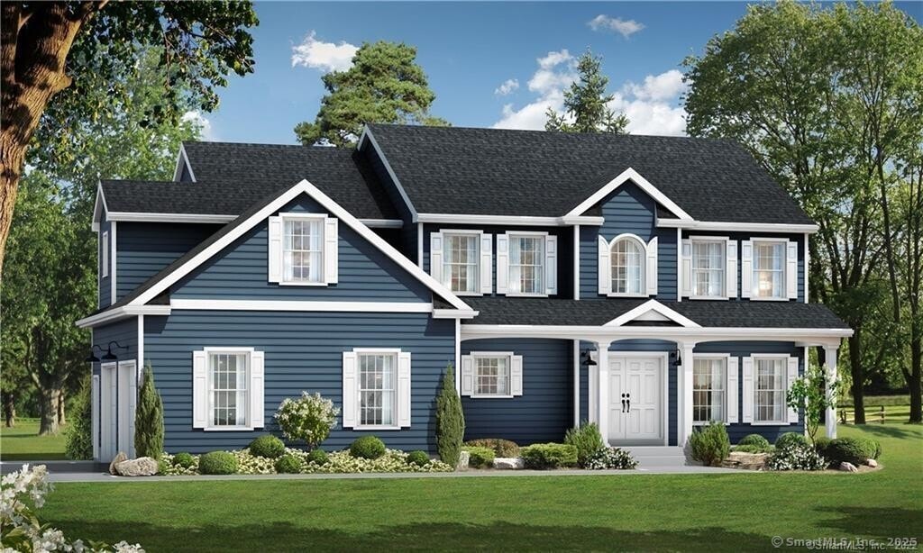 colonial inspired home with a shingled roof and a front yard