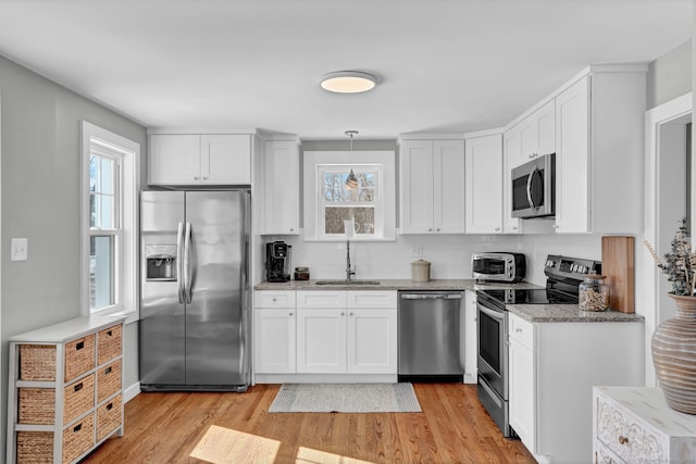 kitchen featuring stainless steel appliances, a sink, and white cabinetry