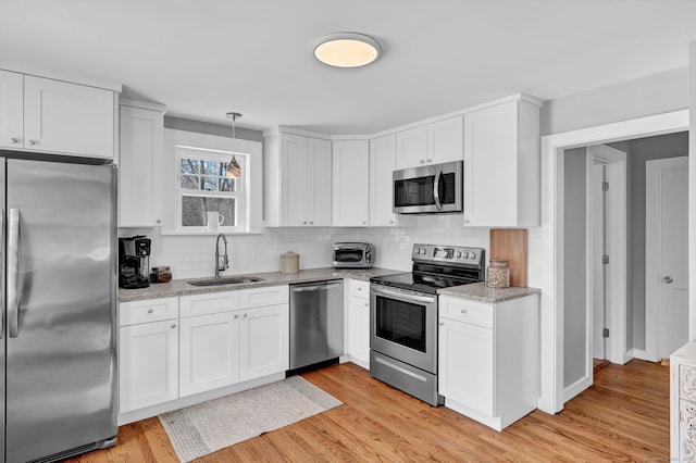 kitchen with stainless steel appliances, light wood-type flooring, white cabinets, and a sink