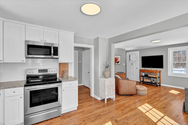 kitchen with white cabinets, light wood-style flooring, stainless steel appliances, and open floor plan