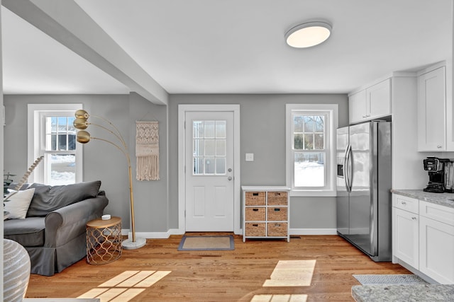 interior space with baseboards, light wood finished floors, and a healthy amount of sunlight