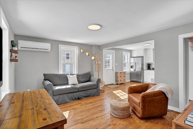 living area featuring light wood finished floors, a wall mounted air conditioner, and baseboards