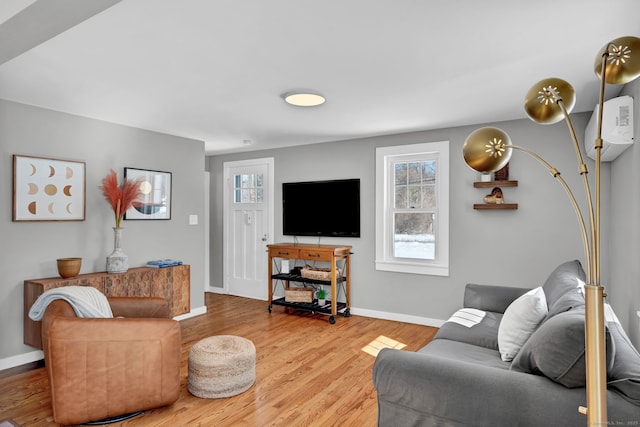 living room with an AC wall unit, baseboards, and wood finished floors