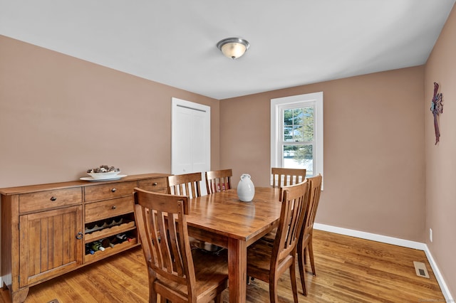 dining room with light wood-type flooring, visible vents, and baseboards