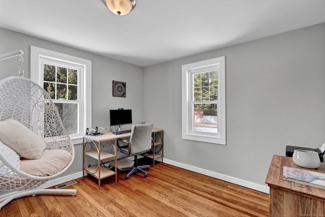 office with plenty of natural light, visible vents, light wood-style flooring, and baseboards