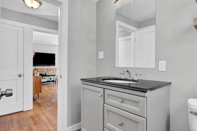 half bathroom with toilet, wood finished floors, and vanity