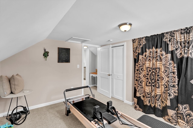 workout room with baseboards, vaulted ceiling, attic access, and light colored carpet