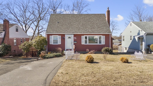 view of front of home featuring a shingled roof, a chimney, and a front yard