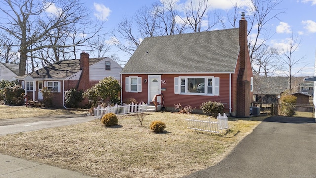 cape cod home with aphalt driveway, a chimney, a shingled roof, fence, and cooling unit