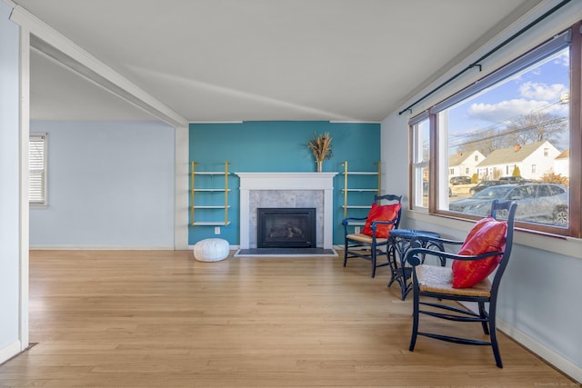 living area featuring light wood-style floors, baseboards, a wealth of natural light, and a tile fireplace