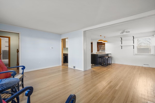 living room featuring baseboards, visible vents, and light wood-style floors