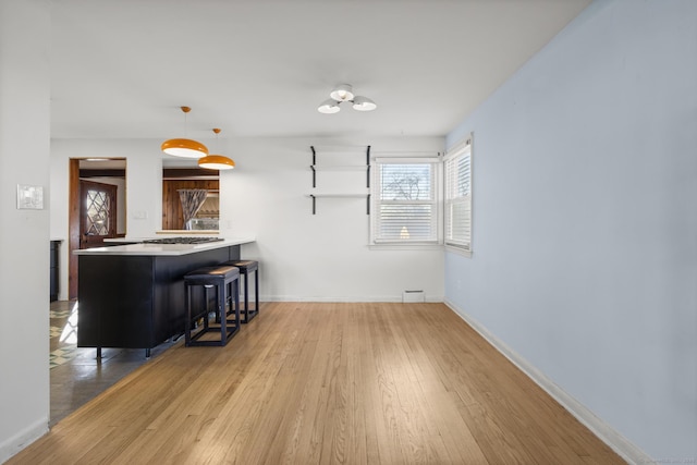 interior space with baseboards, wood finished floors, and decorative light fixtures