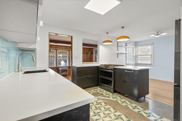 kitchen featuring modern cabinets, range with two ovens, a sink, and light countertops