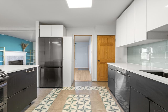 kitchen featuring light countertops, appliances with stainless steel finishes, backsplash, and white cabinets