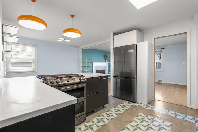 kitchen with dark cabinets, stainless steel appliances, visible vents, light countertops, and decorative light fixtures