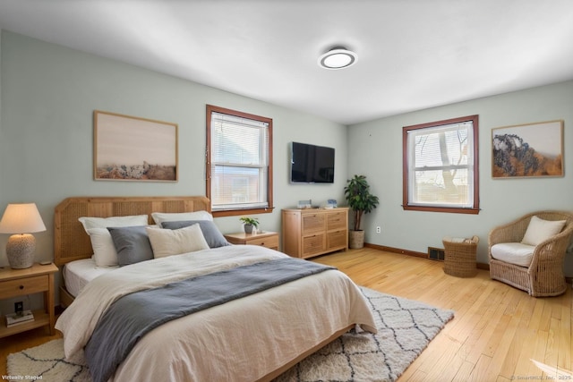 bedroom with visible vents, hardwood / wood-style flooring, and baseboards