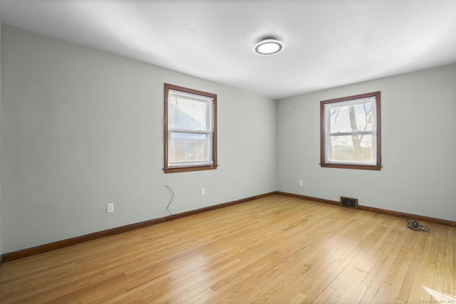 unfurnished room with light wood-style floors, visible vents, and baseboards